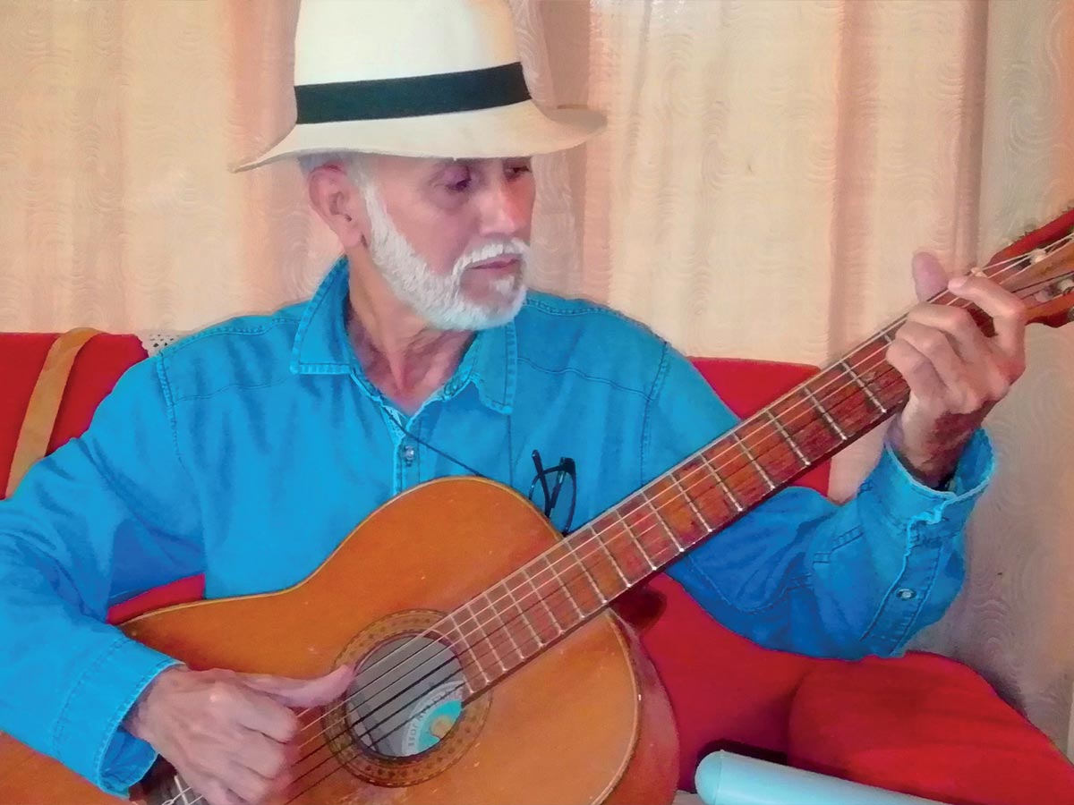 El escritor e ingeniero agrónomo, Santiago Porras Jiménez en su casa de habitación tocando y cantando “Minero viejo”.